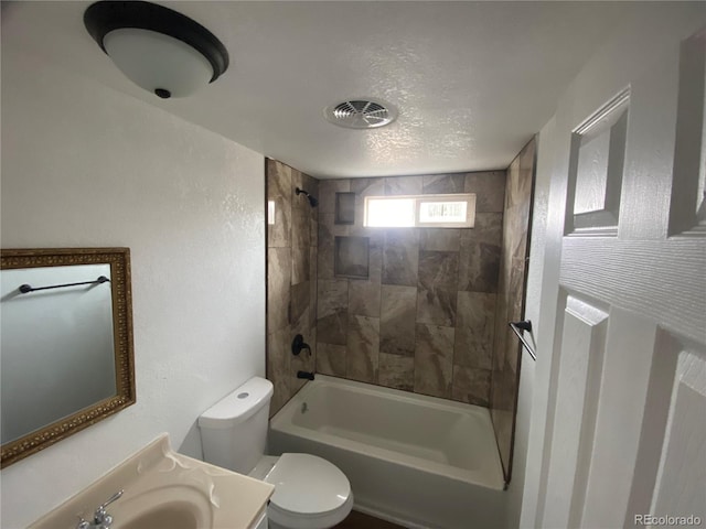 full bathroom with tiled shower / bath combo, vanity, a textured ceiling, and toilet