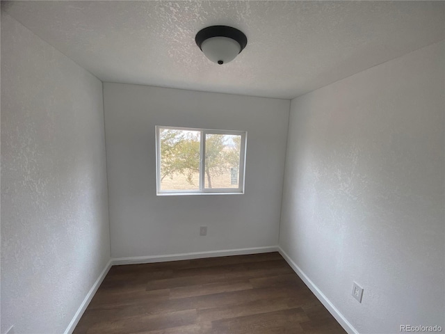 empty room with dark wood-type flooring and a textured ceiling