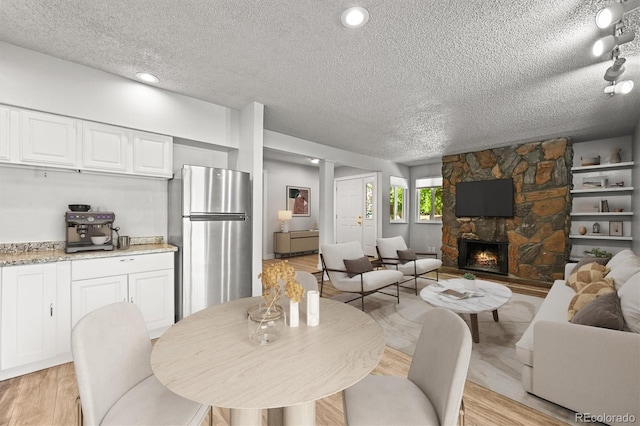 2678 S Xanadu Way Unit C, Aurora, CO 80014 - dining space featuring a textured ceiling, light wood-type flooring, a fireplace, and recessed lighting