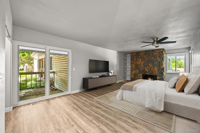 2678 S Xanadu Way Unit C, Aurora, CO 80014 - bedroom with access to outside, wood finished floors, a textured ceiling, a fireplace, and a ceiling fan