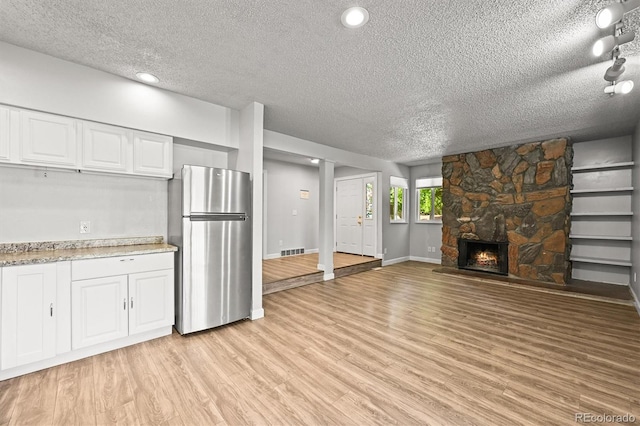 2678 S Xanadu Way Unit C, Aurora, CO 80014 - kitchen featuring freestanding refrigerator, a textured ceiling, light wood-type flooring, white cabinetry, and open floor plan