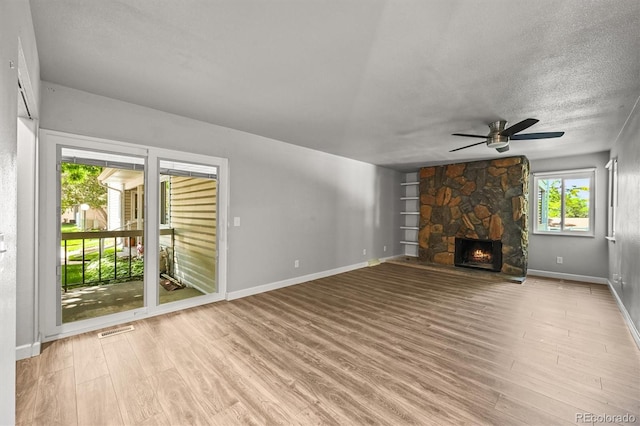 2678 S Xanadu Way Unit C, Aurora, CO 80014 - unfurnished living room featuring ceiling fan, wood finished floors, a textured ceiling, and a stone fireplace