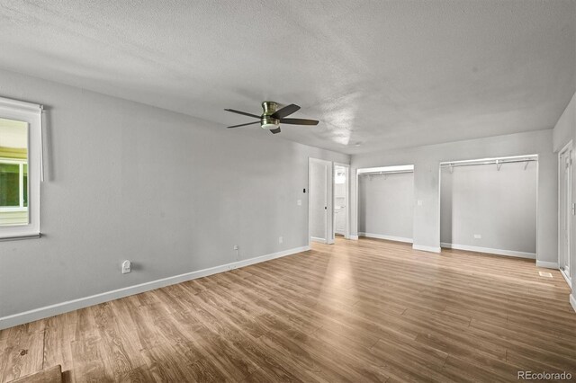 2678 S Xanadu Way Unit C, Aurora, CO 80014 - unfurnished bedroom with multiple closets, a textured ceiling, wood finished floors, and a ceiling fan