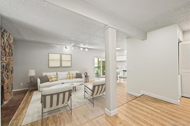 2678 S Xanadu Way Unit C, Aurora, CO 80014 - living area featuring a textured ceiling, light wood finished floors, rail lighting, and decorative columns