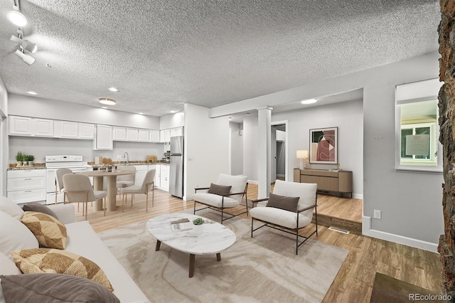 2678 S Xanadu Way Unit C, Aurora, CO 80014 - living area featuring light wood-style floors, a textured ceiling, decorative columns, and recessed lighting