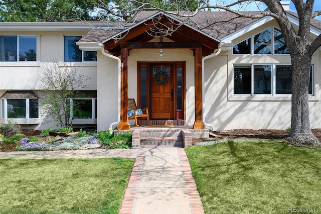 entrance to property with stucco siding and a yard