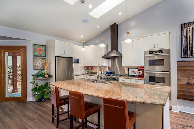 kitchen with stainless steel appliances, wall chimney range hood, a sink, a skylight, and baseboards