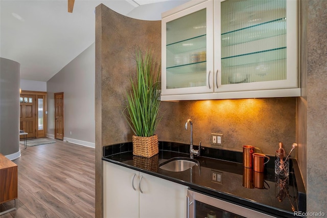indoor wet bar with vaulted ceiling, wood finished floors, backsplash, and wine cooler