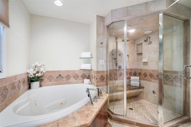 bathroom with a tub with jets, a shower stall, and recessed lighting