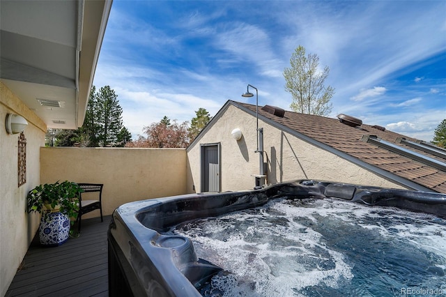 view of property exterior with a hot tub and stucco siding