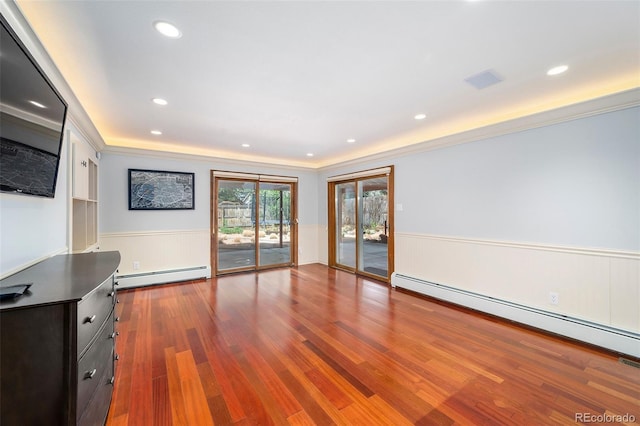 unfurnished living room with baseboard heating, a wainscoted wall, ornamental molding, wood finished floors, and recessed lighting