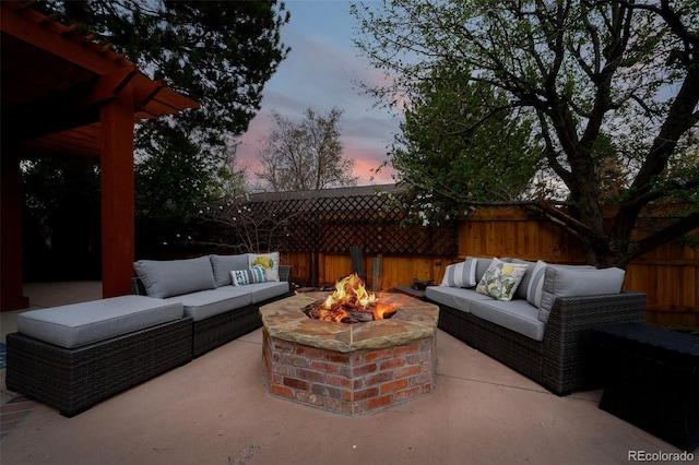 patio terrace at dusk featuring an outdoor living space with a fire pit and a fenced backyard