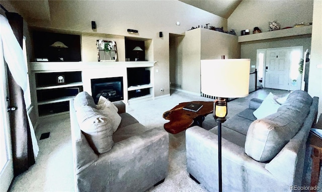 690 Antelope Dr, Bennett, CO 80102 - living room with built in shelves, high vaulted ceiling, a glass covered fireplace, and baseboards