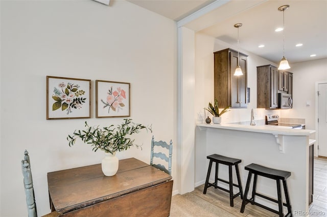 304 Barnwood Dr, Buena Vista, CO 81211 - kitchen with appliances with stainless steel finishes, light countertops, a kitchen breakfast bar, recessed lighting, and dark brown cabinets