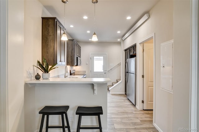 304 Barnwood Dr, Buena Vista, CO 81211 - kitchen featuring stainless steel appliances, light countertops, a breakfast bar, dark brown cabinetry, and a peninsula