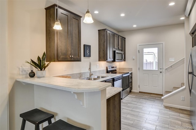 304 Barnwood Dr, Buena Vista, CO 81211 - kitchen with stainless steel appliances, light countertops, a breakfast bar area, dark brown cabinets, and hanging light fixtures