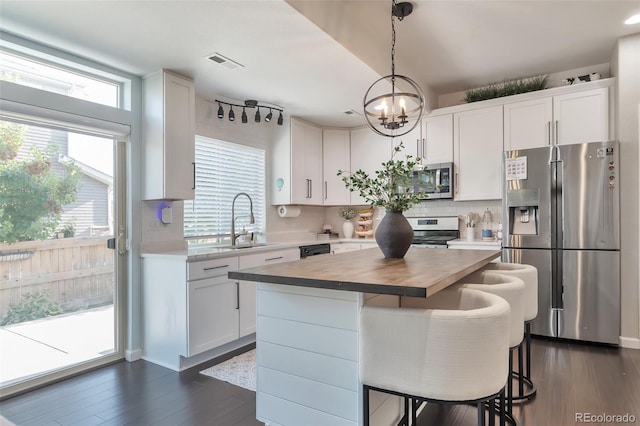 18096 E 104th Way, Commerce City, CO 80022 - kitchen with appliances with stainless steel finishes, healthy amount of natural light, a chandelier, and white cabinets