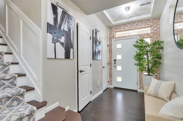 18096 E 104th Way, Commerce City, CO 80022 - entrance foyer featuring dark wood-style floors, stairs, a raised ceiling, and brick wall