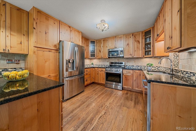 9745 Hilldale Dr, Morrison, CO 80465 - kitchen with appliances with stainless steel finishes, light wood-style flooring, backsplash, and glass insert cabinets