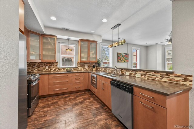 1717 E 22nd Ave, Denver, CO 80205 - kitchen featuring appliances with stainless steel finishes, a sink, a peninsula, decorative backsplash, and dark wood-type flooring