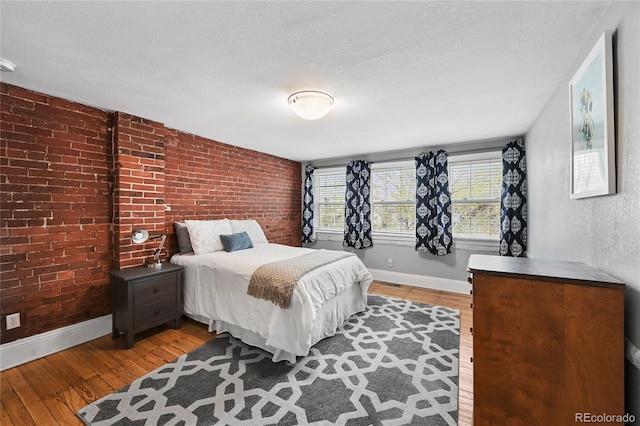 1717 E 22nd Ave, Denver, CO 80205 - bedroom featuring baseboards, a textured ceiling, brick wall, and wood finished floors