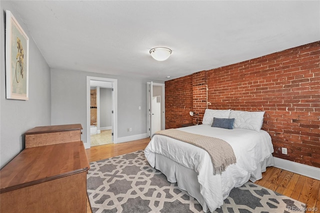1717 E 22nd Ave, Denver, CO 80205 - bedroom with baseboards, brick wall, and wood finished floors