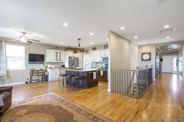 3560 Zane Gray Loop, Parker, CO 80138 - kitchen featuring arched walkways, appliances with stainless steel finishes, light wood-style floors, ceiling fan, and a kitchen breakfast bar