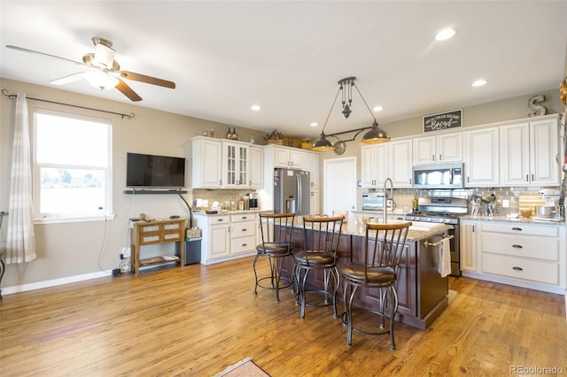 3560 Zane Gray Loop, Parker, CO 80138 - kitchen featuring stainless steel appliances, tasteful backsplash, white cabinetry, a kitchen breakfast bar, and light wood-type flooring