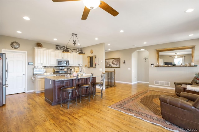 3560 Zane Gray Loop, Parker, CO 80138 - kitchen with ceiling fan, arched walkways, a breakfast bar, light wood-style floors, and appliances with stainless steel finishes
