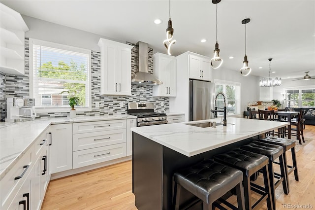 4059 Quivas St, Denver, CO 80211 - kitchen featuring wall chimney exhaust hood, appliances with stainless steel finishes, a kitchen breakfast bar, recessed lighting, and white cabinets