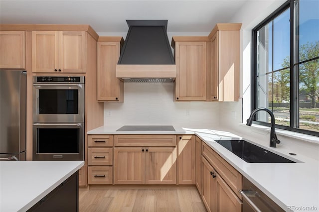 kitchen with a sink, light brown cabinets, stainless steel appliances, and custom range hood