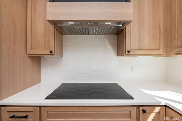 kitchen with black electric stovetop, light countertops, custom range hood, and tasteful backsplash