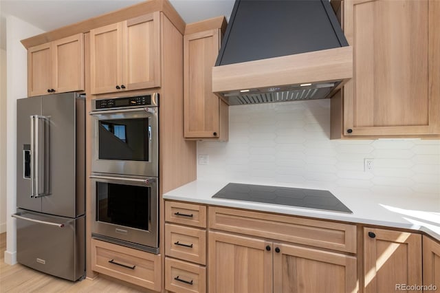 kitchen featuring light countertops, light brown cabinetry, stainless steel appliances, and custom range hood
