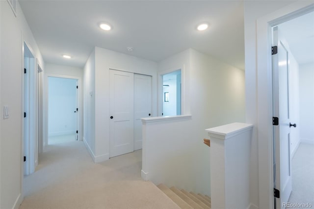 hall featuring light colored carpet, baseboards, an upstairs landing, and recessed lighting