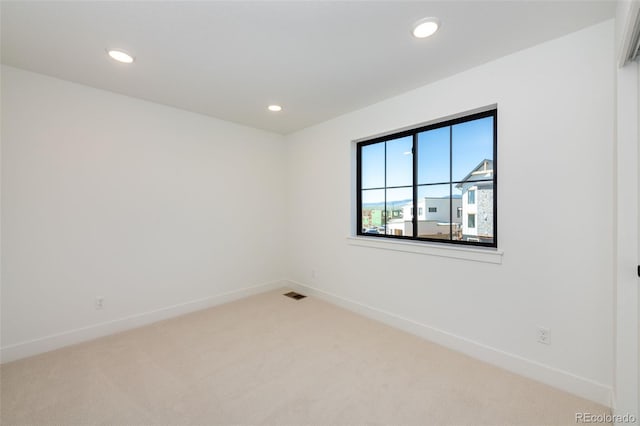empty room with baseboards, visible vents, recessed lighting, and light colored carpet