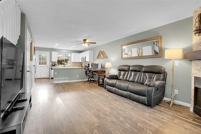 9615 W Chatfield Ave Unit C, Littleton, CO 80128 - living room featuring light wood-style floors, ceiling fan, a stone fireplace, and recessed lighting