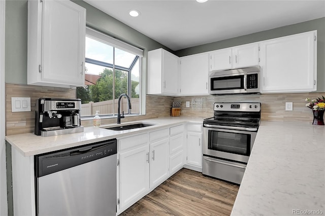9615 W Chatfield Ave Unit C, Littleton, CO 80128 - kitchen featuring stainless steel appliances, white cabinetry, tasteful backsplash, recessed lighting, and wood finished floors
