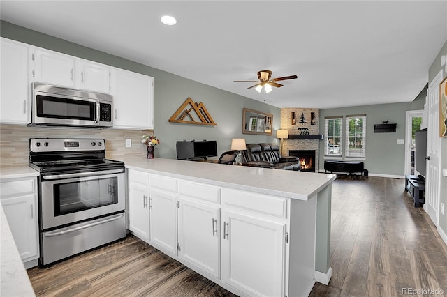 9615 W Chatfield Ave Unit C, Littleton, CO 80128 - kitchen with appliances with stainless steel finishes, a peninsula, light countertops, a ceiling fan, and a large fireplace