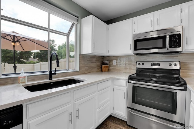 9615 W Chatfield Ave Unit C, Littleton, CO 80128 - kitchen featuring appliances with stainless steel finishes, white cabinets, light stone counters, and tasteful backsplash