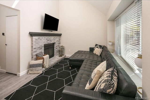 living room with lofted ceiling, wood-type flooring, and a brick fireplace