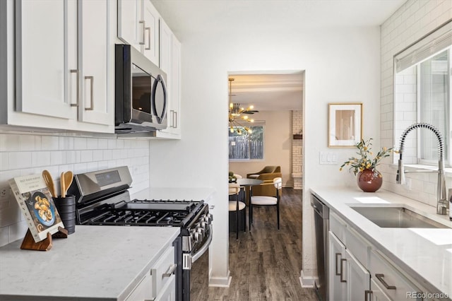 4500 Zephyr St, Wheat Ridge, CO 80033 - kitchen featuring appliances with stainless steel finishes, a sink, a chandelier, backsplash, and dark wood-style floors