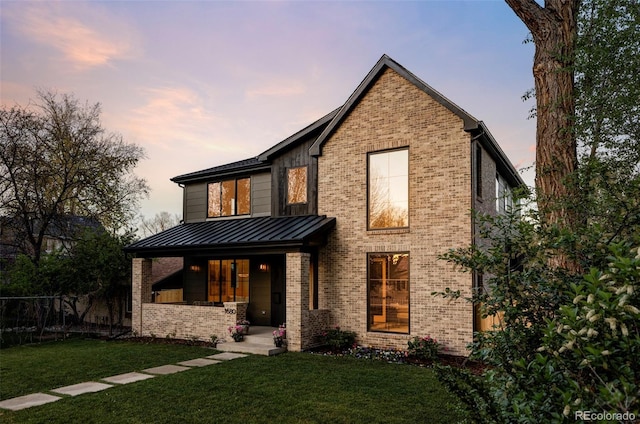 1680 S Humboldt St, Denver, CO 80210 - back of house at dusk featuring a standing seam roof, brick siding, covered porch, and metal roof