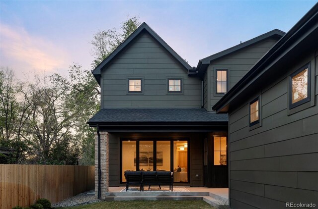 1680 S Humboldt St, Denver, CO 80210 - back of property at dusk with fence, a shingled roof, and outdoor lounge area
