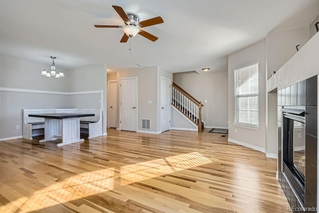 interior space with ceiling fan with notable chandelier and light hardwood / wood-style floors