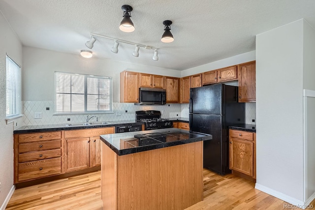 kitchen featuring a center island, black appliances, sink, a textured ceiling, and light hardwood / wood-style floors