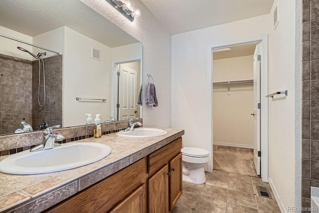 bathroom with vanity, a shower, tile patterned floors, toilet, and a textured ceiling