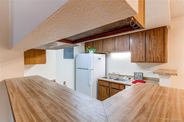 kitchen with white refrigerator, sink, electric panel, and kitchen peninsula