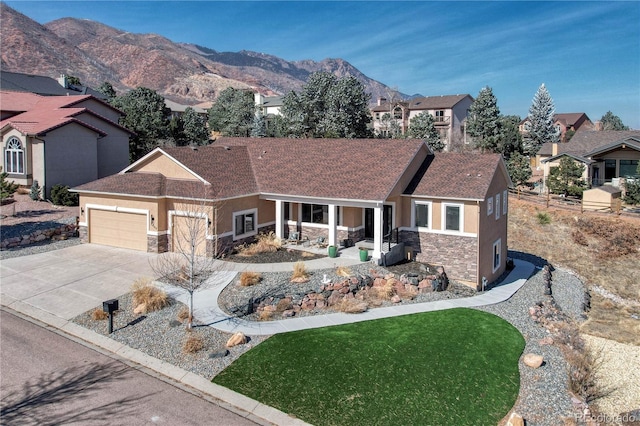 view of front of property with stone siding, an attached garage, driveway, and stucco siding