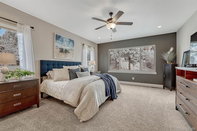 bedroom with light colored carpet, multiple windows, ceiling fan, and baseboards