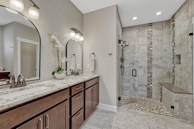 bathroom with double vanity, a shower stall, and a sink